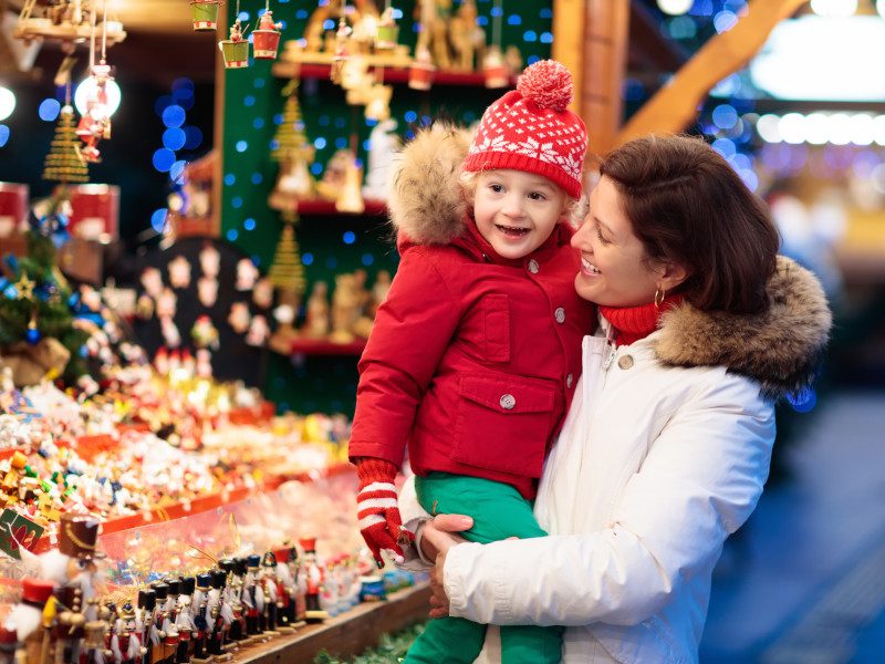 mom and child next to christmas stand